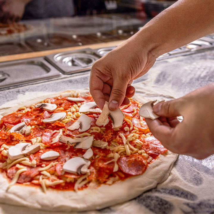 champignon op pizza leggen